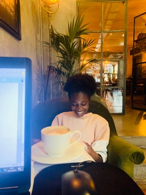 Child smiling in a coffee shop. Picture taken from behind a laptop screen.